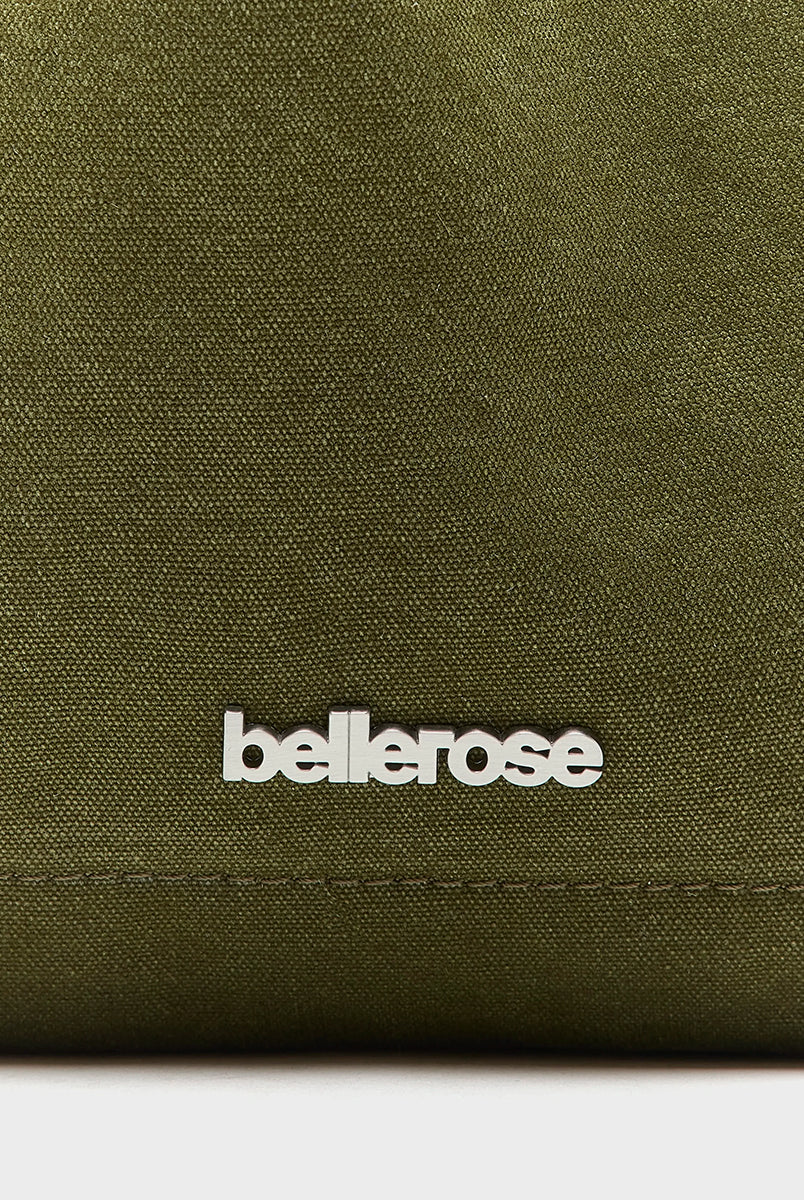 Oliwkowozielona płócienna torba Singa Olive marki BELLEROSE ze skórzanymi wykończeniami i srebrnym, metalowym logo. Posiada skórzaną rączkę oraz odpinany pasek na ramię. Zapinana na metalowy zatrzask z haczykiem. W środku ma główną kieszeń oraz dodatkową kieszonkę z tkaną metką marki. 