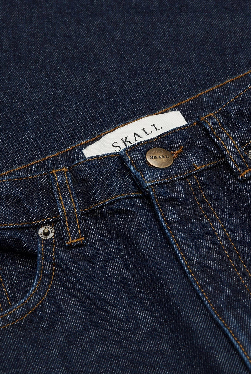 Luźne jeansy Willow Indigo Blue SKALL z obniżonym stanem i szerokimi, prostymi nogawkami. Posiadają kieszenie, szlufki na pasek i haftowane logo z tyłu w pasie. Jeansy maja standardową długość. Wykonane ze sztywnego denimu z bawełny organicznej.