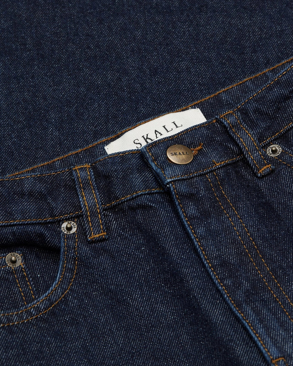 Luźne jeansy Willow Indigo Blue SKALL z obniżonym stanem i szerokimi, prostymi nogawkami. Posiadają kieszenie, szlufki na pasek i haftowane logo z tyłu w pasie. Jeansy maja standardową długość. Wykonane ze sztywnego denimu z bawełny organicznej.