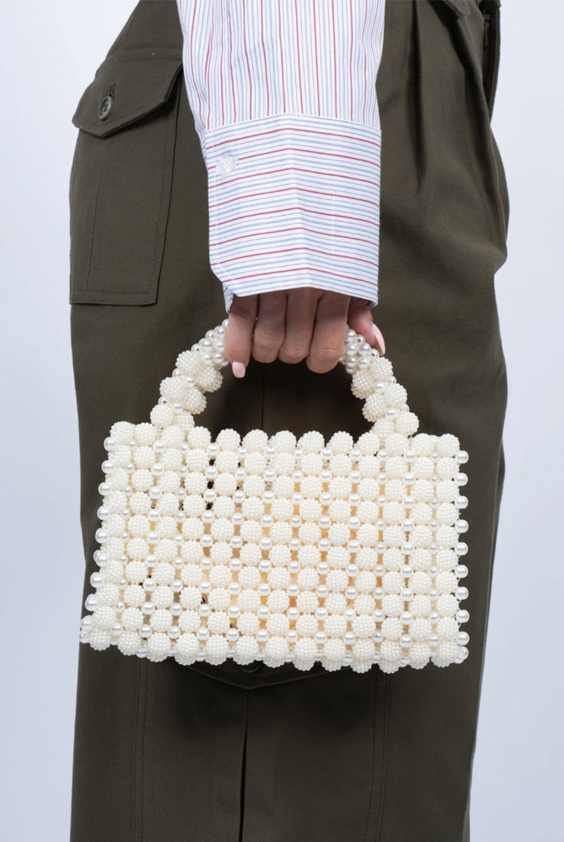 Ręcznie zdobiona torebka z pereł Pearl White SUI AVA. Jej kompaktowy rozmiar sprawia, że idealnie nadaje się na imprezy, kolacje lub jako elegancki dodatek do codziennych stylizacji. Dzięki solidnej konstrukcji perełek i eleganckiemu uchwytowi jest zarówno piękna, jak i funkcjonalna- idealna do noszenia najpotrzebniejszych rzeczy.