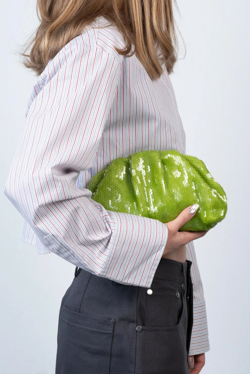 Torebka kopertówka Sequin Clutch Green SUI AVA o miękkiej powierzchni pokrytej połyskującymi cekinami. Jej elastyczny kształt nadaje jej swobodny, a zarazem elegancki wygląd. To idealny dodatek do Twojej stylizacji. Pomieści niezbędne drobiazgi, takie jak telefon, klucze i szminkę. Noś ją w dłoni jak elegancką kopertówkę. 