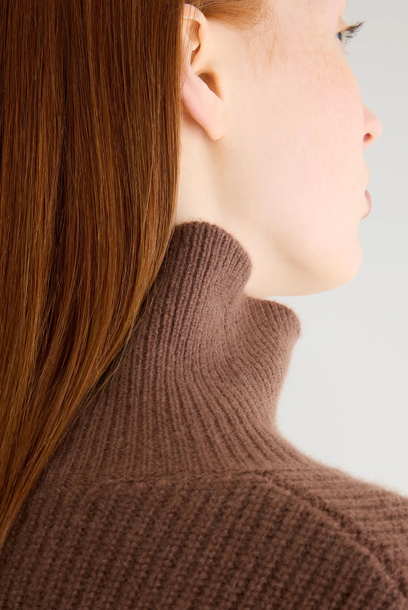 Luźny, brązowy sweter z golfem Synin Tiramisu Bellerose wykonany w 100% z kaszmiru. Posiada proste, szerokie rękawy z wywiniętymi mankietami i kołnierz typu funnel neck. Ma swobodny, lekko luźny krój oraz wyraźną, prążkowaną strukturę materiału. Wysoki, otulający golf dodaje mu szyku i doskonale sprawdza się w chłodniejsze dni, tworząc stylową kompozycję z ciemnymi spodniami.
-Golf
-Długie, szerokie rękawy
-100% kaszmir