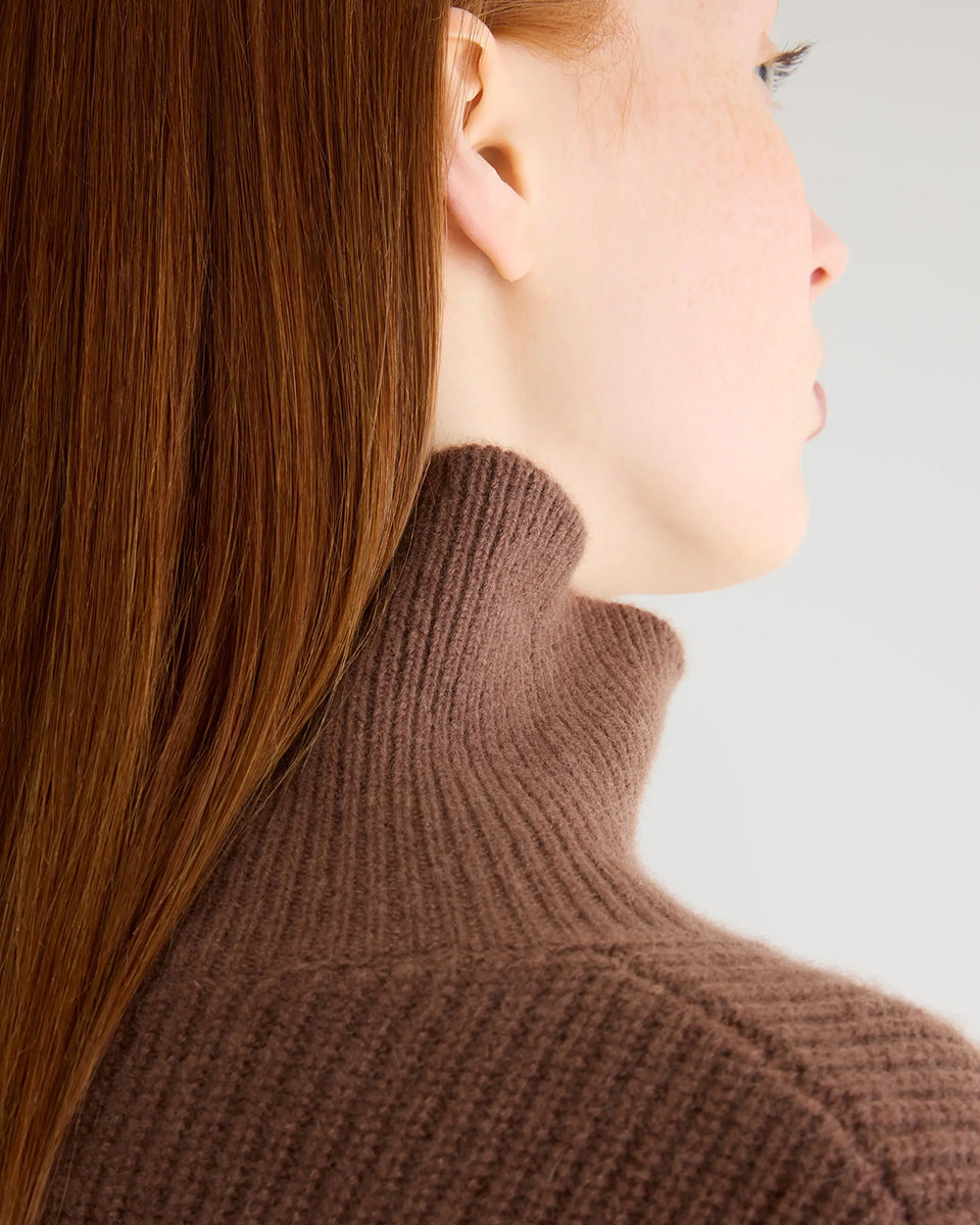 Luźny, brązowy sweter z golfem Synin Tiramisu Bellerose wykonany w 100% z kaszmiru. Posiada proste, szerokie rękawy z wywiniętymi mankietami i kołnierz typu funnel neck. Ma swobodny, lekko luźny krój oraz wyraźną, prążkowaną strukturę materiału. Wysoki, otulający golf dodaje mu szyku i doskonale sprawdza się w chłodniejsze dni, tworząc stylową kompozycję z ciemnymi spodniami.
-Golf
-Długie, szerokie rękawy
-100% kaszmir
