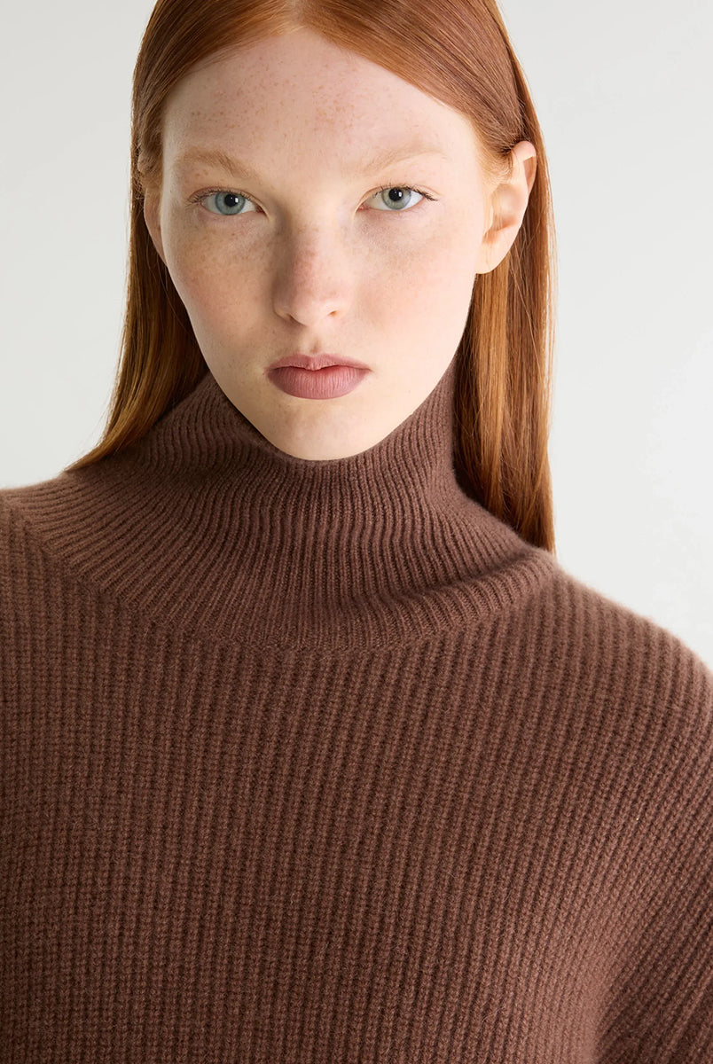 Luźny, brązowy sweter z golfem Synin Tiramisu Bellerose wykonany w 100% z kaszmiru. Posiada proste, szerokie rękawy z wywiniętymi mankietami i kołnierz typu funnel neck. Ma swobodny, lekko luźny krój oraz wyraźną, prążkowaną strukturę materiału. Wysoki, otulający golf dodaje mu szyku i doskonale sprawdza się w chłodniejsze dni, tworząc stylową kompozycję z ciemnymi spodniami.
-Golf
-Długie, szerokie rękawy
-100% kaszmir