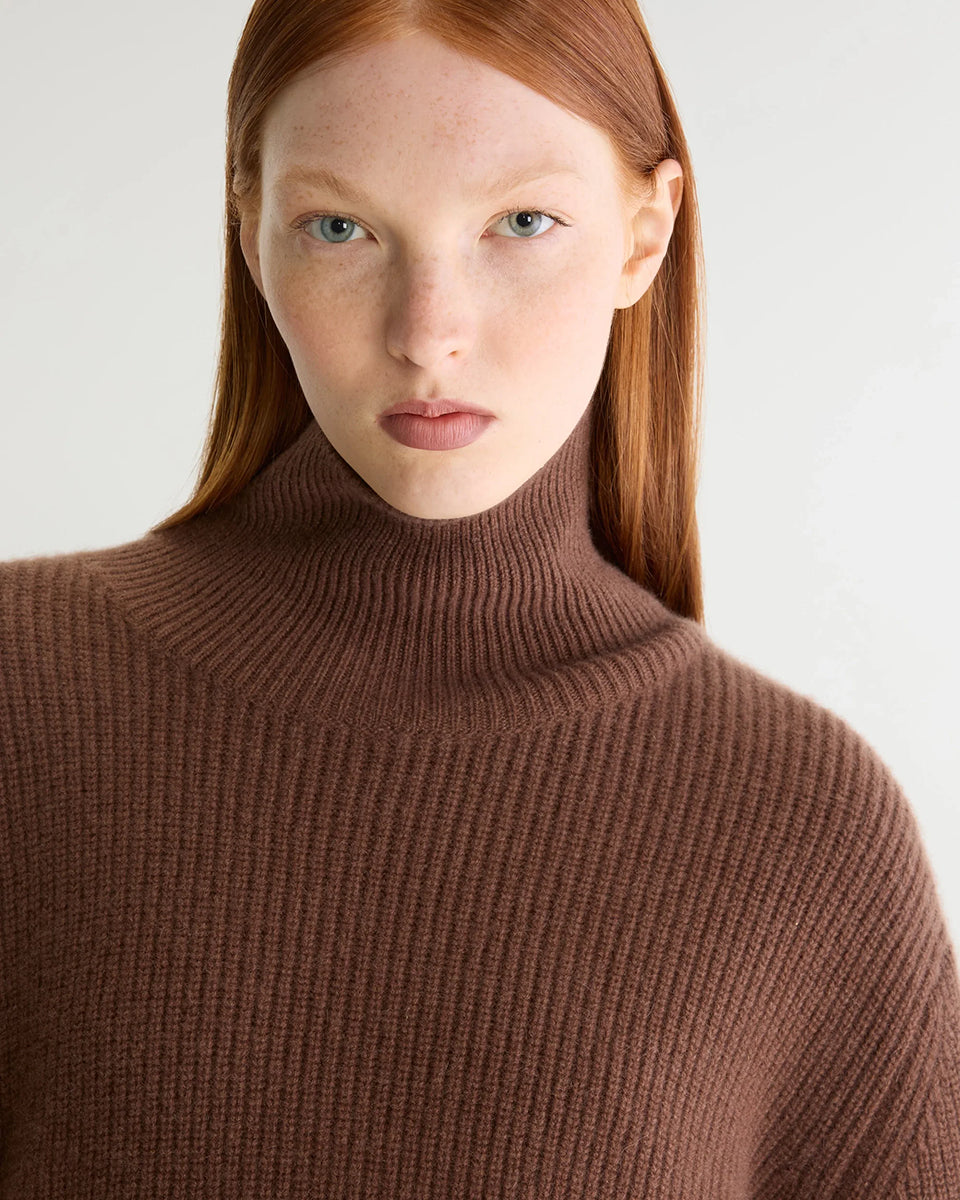 Luźny, brązowy sweter z golfem Synin Tiramisu Bellerose wykonany w 100% z kaszmiru. Posiada proste, szerokie rękawy z wywiniętymi mankietami i kołnierz typu funnel neck. Ma swobodny, lekko luźny krój oraz wyraźną, prążkowaną strukturę materiału. Wysoki, otulający golf dodaje mu szyku i doskonale sprawdza się w chłodniejsze dni, tworząc stylową kompozycję z ciemnymi spodniami.
-Golf
-Długie, szerokie rękawy
-100% kaszmir