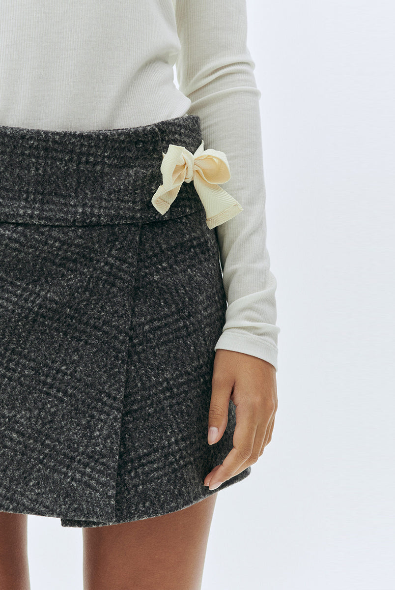 Szara, tweedowa spódnica mini z niskim stanem Brad The Garment w delikatną, czarną kratę. Z boku dekorowana uroczą, białą kokardą