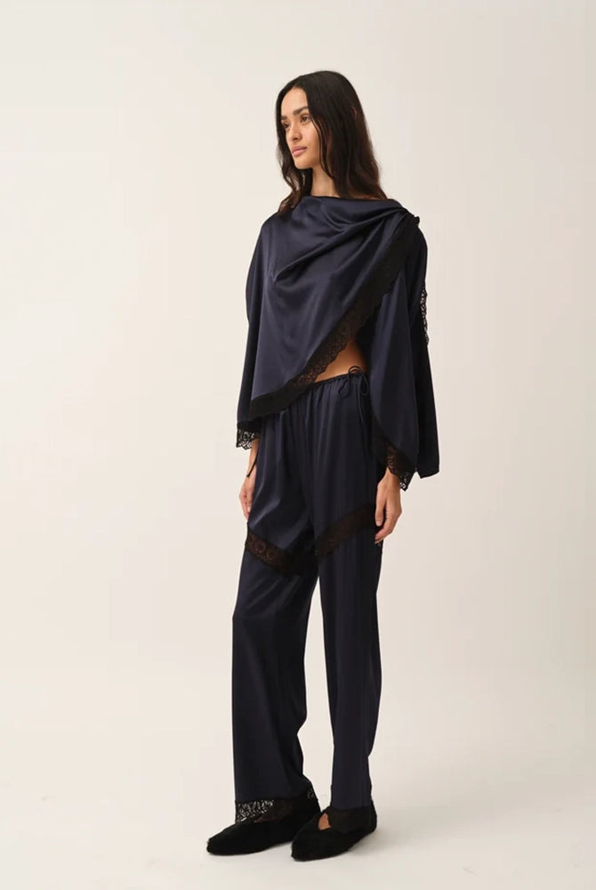 Elegancka, jedwabna peleryna Cata The Garment o asymetrycznym fasonie. Zebrana na lewym ramieniu. Wykończona zmysłową koronką. Wykonana z lejącej, jedwabnej tkaniny.