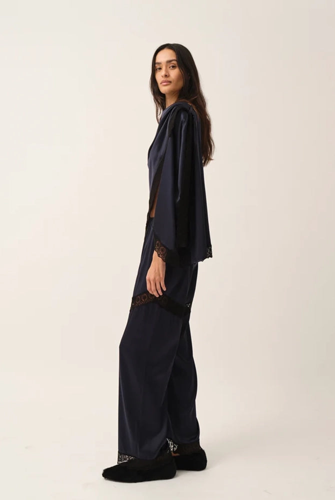 Elegancka, jedwabna peleryna Cata The Garment o asymetrycznym fasonie. Zebrana na lewym ramieniu. Wykończona zmysłową koronką. Wykonana z lejącej, jedwabnej tkaniny.