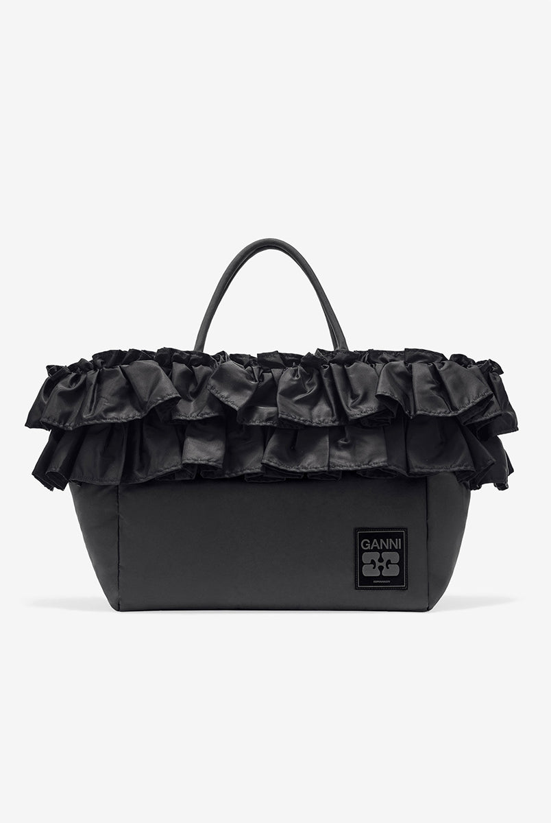 Torba typu tote 7188 XXL Shopper Black marki GANNI z uchwytami. Posiada jedną dużą komorę z wewnętrzną kieszenią zapinaną na zamek. U dołu znajduje się niewielkie logo marki. Wyjątkowości dodaje zdobienie w postaci falbanek. Zaprojektowana, aby pomieścić telefon, portfel, okulary przeciwsłoneczne, klucze, butelkę z wodą, saszetkę, strój sportowy i laptopa.