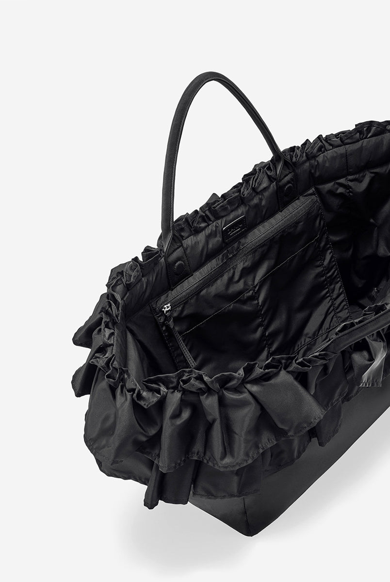 Torba typu tote 7188 XXL Shopper Black marki GANNI z uchwytami. Posiada jedną dużą komorę z wewnętrzną kieszenią zapinaną na zamek. U dołu znajduje się niewielkie logo marki. Wyjątkowości dodaje zdobienie w postaci falbanek. Zaprojektowana, aby pomieścić telefon, portfel, okulary przeciwsłoneczne, klucze, butelkę z wodą, saszetkę, strój sportowy i laptopa.