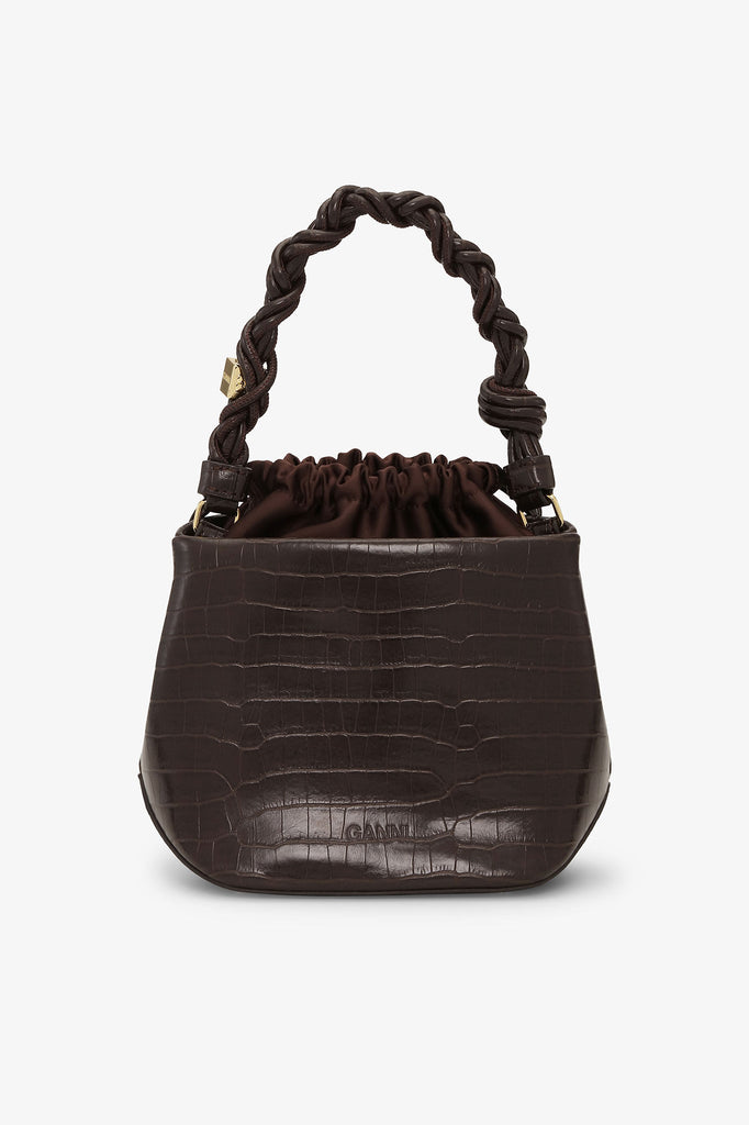 Niewielka, ciemnobrązowa torebka Bou Bucket 6697 GANNI o teksturze skóry krokodyla z plecionym uchwytem oraz regulowanym, odpinanym paskiem.
