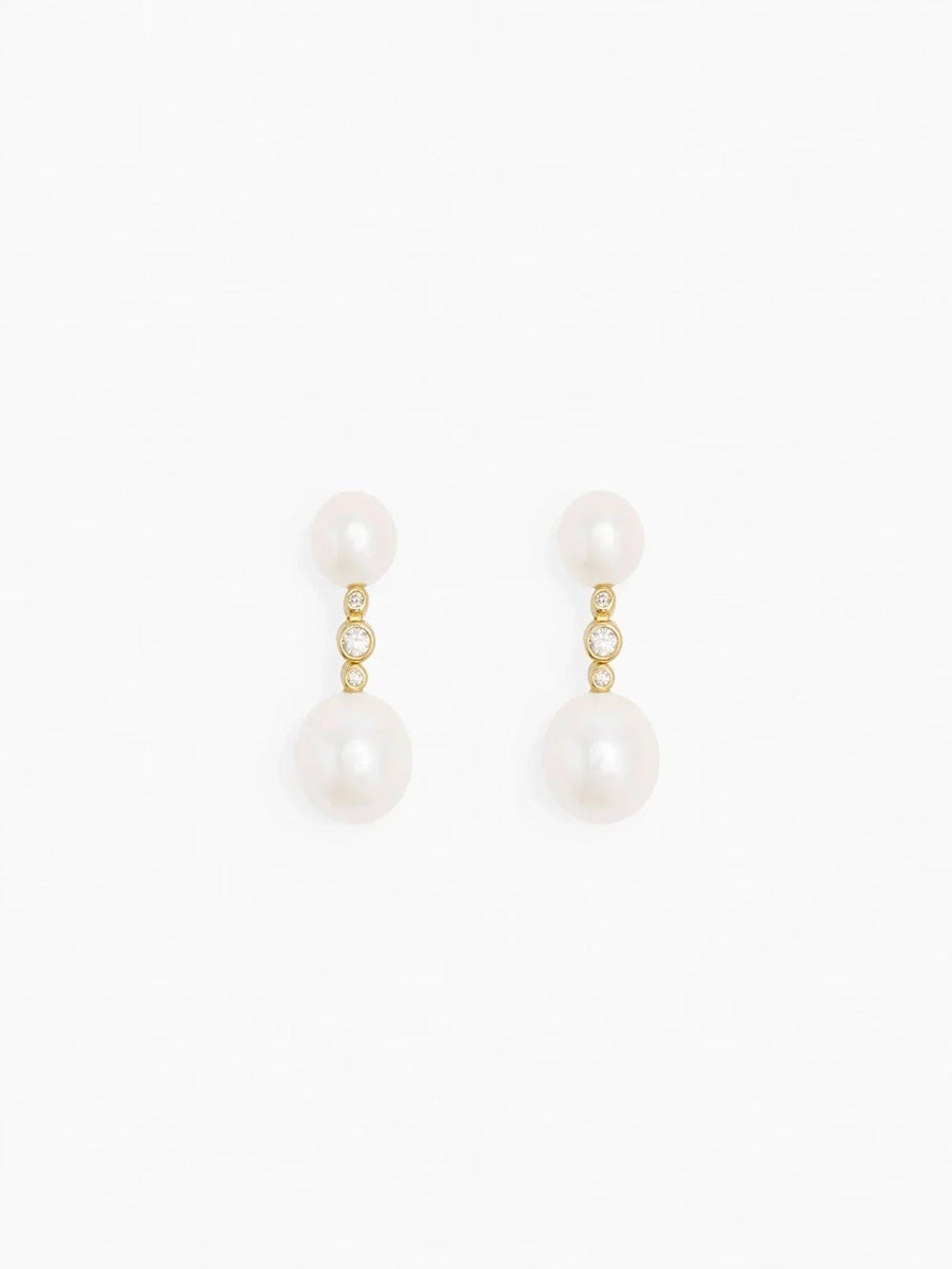 Delikatne, wiszące kolczyki 12113 Odile Pearl RAGBAG z naturalnymi perłami połączonymi pozłacanym łańcuszkiem z niewielką, białą cyrkonią. Zapinane na sztyft.
