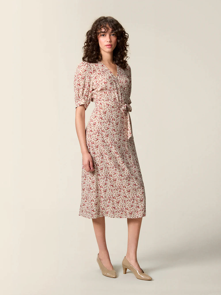 Zwiewna, kopertowa sukienka w kwiatowy print Rosalina Rouje z krótkimi, bufiastymi rękawami i trójkątnym dekoltem. Dopasowana i wiązana w talii za pomocą paska. Sukienka ma długość za kolana. 