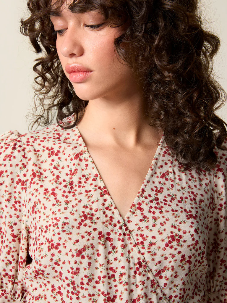 Zwiewna, kopertowa sukienka w kwiatowy print Rosalina Rouje z krótkimi, bufiastymi rękawami i trójkątnym dekoltem. Dopasowana i wiązana w talii za pomocą paska. Sukienka ma długość za kolana. 