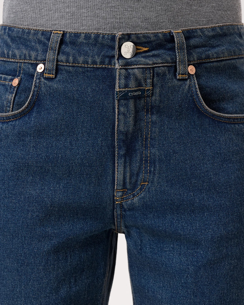 Granatowe jeansy Milo marki CLOSED ze średnim stanem i prostą, luźną i skróconą nogawką. Przylegające w biodrach. Spodnie mają pięć kieszeni. Zapinane na guzik i zamek błyskawiczny. Przy rozporku posiadają niewielką, charakterystyczną dla marki naszywkę z logo CLOSED. 