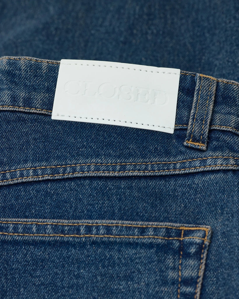 Granatowe jeansy Milo marki CLOSED ze średnim stanem i prostą, luźną i skróconą nogawką. Przylegające w biodrach. Spodnie mają pięć kieszeni. Zapinane na guzik i zamek błyskawiczny. Przy rozporku posiadają niewielką, charakterystyczną dla marki naszywkę z logo CLOSED. 