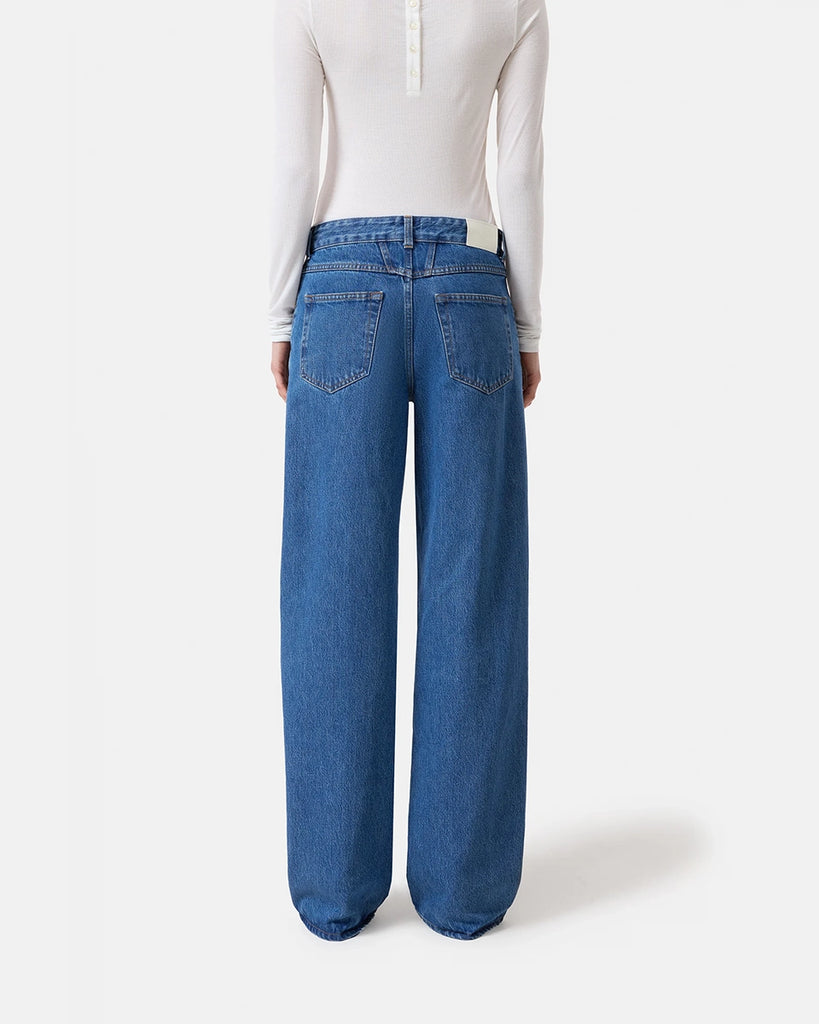 Granatowe jeansy Nikka CLOSED ze średnim stanem i luźną, długą luźną, prostą nogawką. Przylegające w biodrach. Posiadają pięć kieszeni. Przy rozporku mają niewielką, charakterystyczną naszywkę z logo marki