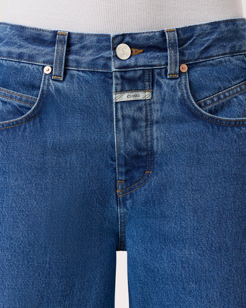 Granatowe jeansy Nikka CLOSED ze średnim stanem i luźną, długą luźną, prostą nogawką. Przylegające w biodrach. Posiadają pięć kieszeni. Przy rozporku mają niewielką, charakterystyczną naszywkę z logo marki