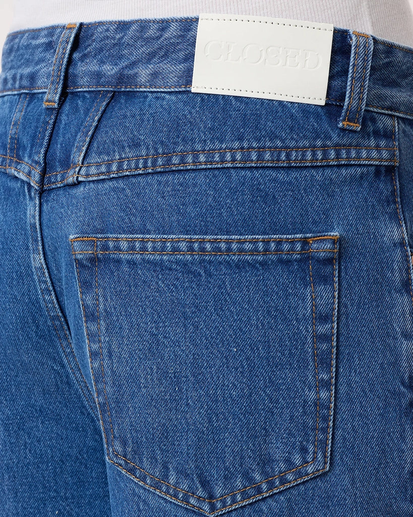 Granatowe jeansy Nikka CLOSED ze średnim stanem i luźną, długą luźną, prostą nogawką. Przylegające w biodrach. Posiadają pięć kieszeni. Przy rozporku mają niewielką, charakterystyczną naszywkę z logo marki