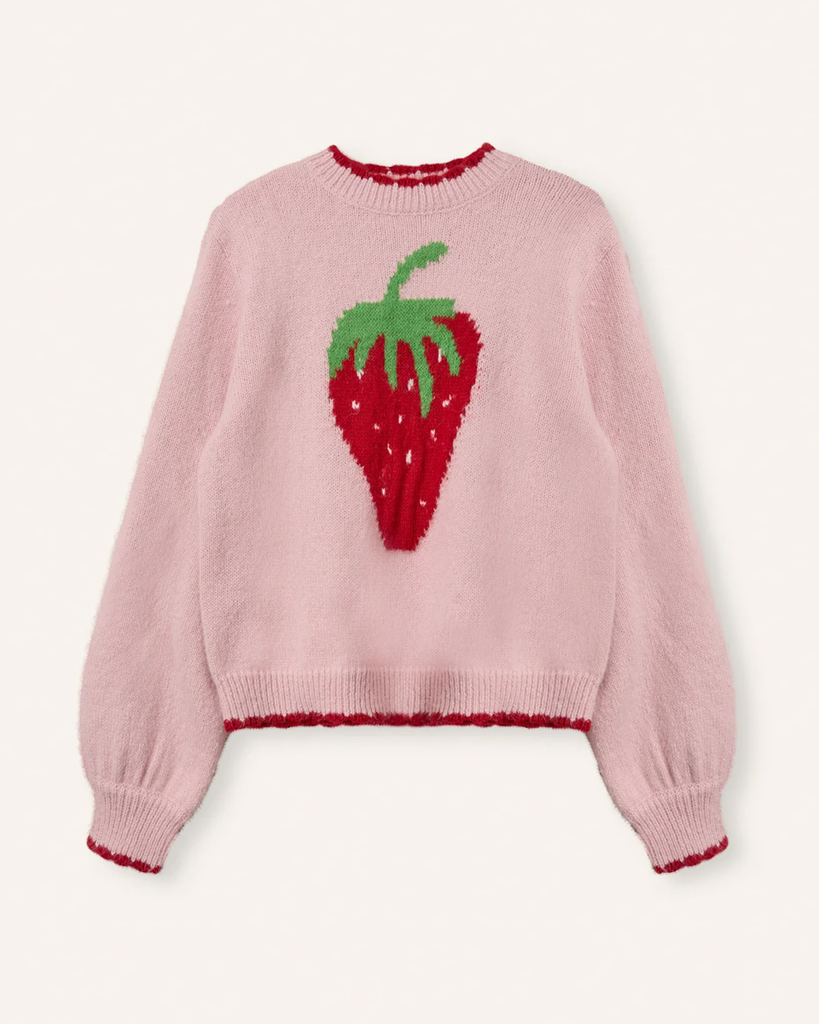 Sweter Freja Rose Strawberry marki Helmstedt w uroczym jasnoróżowym kolorze z motywem truskawki na przodzie. Posiada czerwone ściągacze przy mankietach i dole, które idealnie komponują się z printem na środku. 