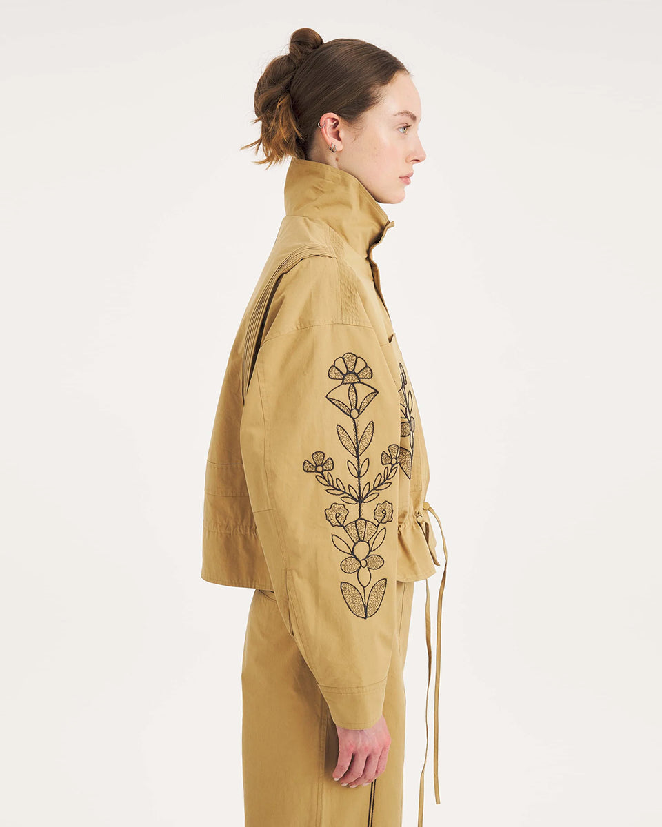 Krótka, strukturalna kurtka Maria Beige Antik Batik o nowoczesnym, nieco geometrycznym kroju. Posiada charakterystyczną, bardzo wysoką stójkę zapinaną na guziki. Regulowana w pasie za pomocą ściągacza ze sznurkami, co tworzy efekt delikatnej baskinki/falbany. Z przodu na kieszeniach oraz na rękawach znajdują się hafty z motywami roślinnymi i kwiatowymi. Dodatkowe, drobne, haftowane przeszycia ozdabiają również linię ramion. Zapinana na guziki.&nbsp;

-Krótki, nowoczesny fason

-Hafty z motywami roślinnymi i