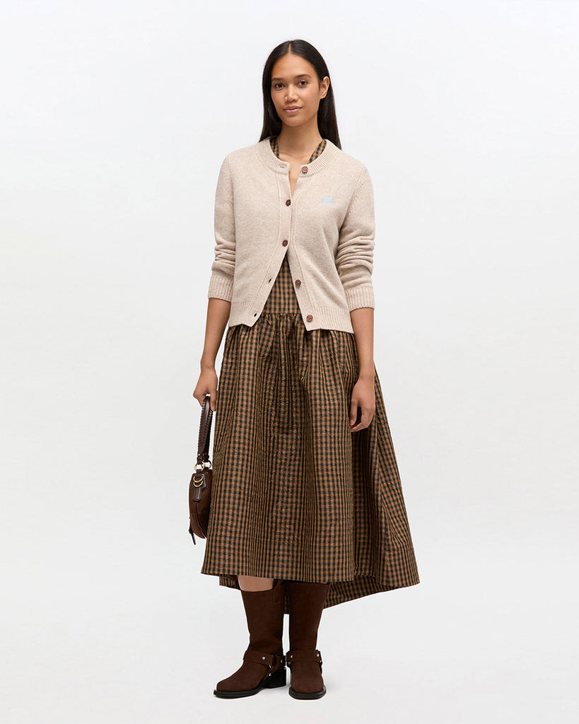 Beżowy kardigan 2594 Sand marki GANNI z okrągłym dekoltem i długimi rękawami. Zapinany na guziki. Na lewej piersi posiada niewielkie, wyhaftowane logo marki. Wykończony ściągaczami. Wykonany z dzianiny z wełną. Zestaw go z ulubioną spódnicą lub klasycznymi jeansami.