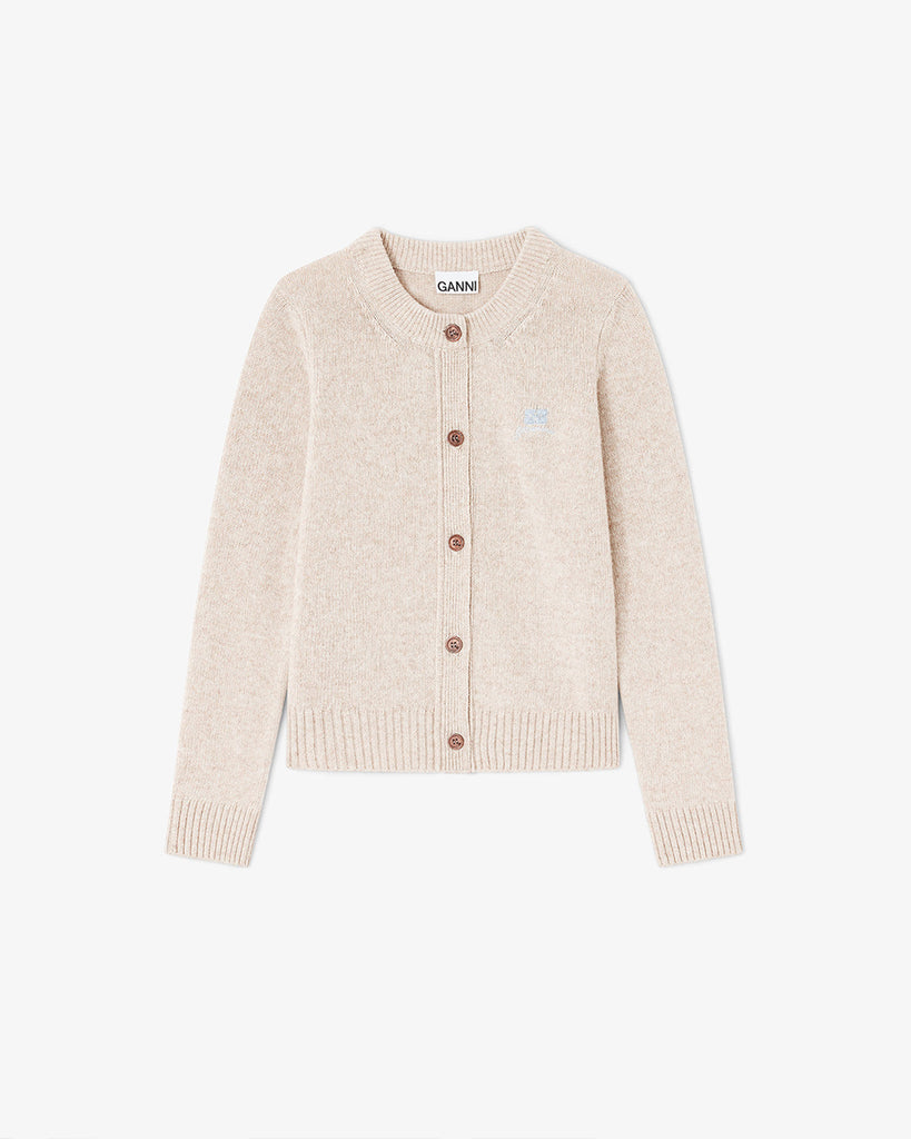 Beżowy kardigan 2594 Sand marki GANNI z okrągłym dekoltem i długimi rękawami. Zapinany na guziki. Na lewej piersi posiada niewielkie, wyhaftowane logo marki. Wykończony ściągaczami. Wykonany z dzianiny z wełną. Zestaw go z ulubioną spódnicą lub klasycznymi jeansami.