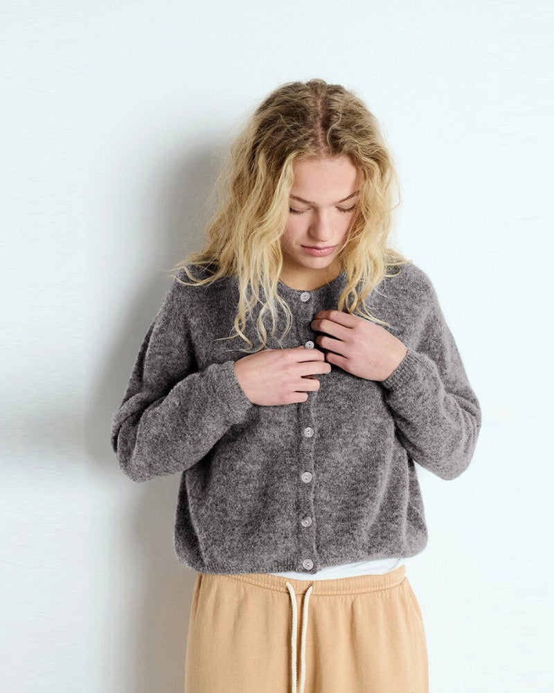 Krótki, kremowy kardigan VITOW American Vintage o pudełkowym fasonie. Posiada okrągły dekolt i opadające ramiona. Zapinany na guziki z imitacji masy perłowej. Wykonany z cienkiej i bardzo miękkiej dzianiny z wełną i alpaką. To klasyczny model, który musi znaleźć się w każdej szafie. Pasuje dosłownie do wszystkiego - ulubionych jeansów, zwiewnej spódnicy, długiej sukienki czy spodni garniturowych