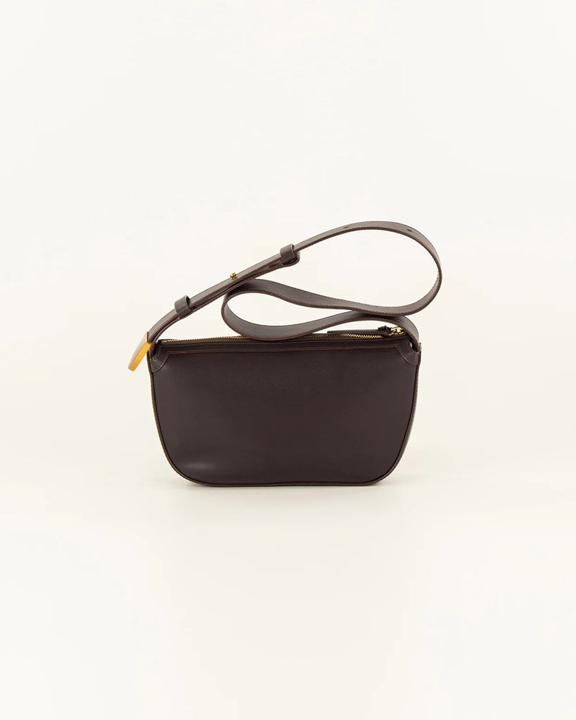 Brązowa skórzana torebka Amo Deep Coffee typu baguette marki Sessun z ręcznie plecionym panelem z przodu. Posiada kieszeń centralną z dodatkową kieszenią naszytą i regulowany pasek na ramię, z zapięciem na ćwieki oraz metalowym, złotym zakończeniem z logo marki.