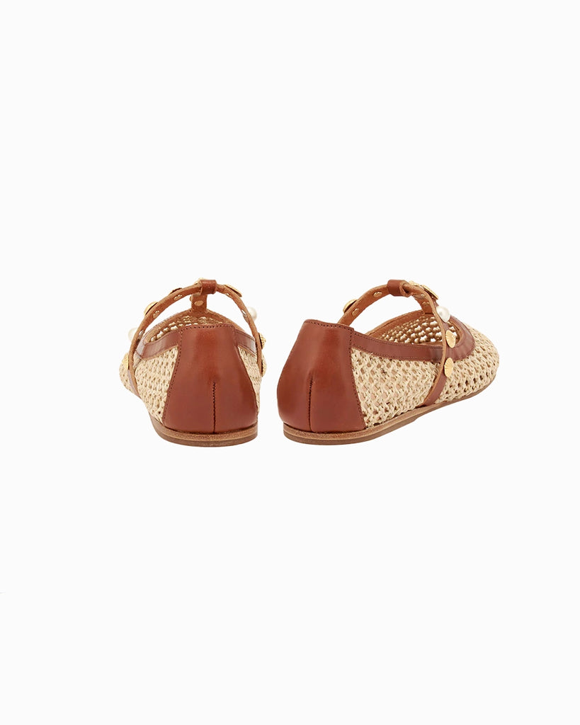 Plecione, ażurowe baletki na płaskiej podeszwie Aerati Ancient Greek Sandals z cienkimi, skórzanymi, skrzyżowanymi paskami dekorowanymi biżuteryjnymi aplikacjami z motywami muszelek i sztucznych pereł. Wykonane z rafii i miękkiej skóry naturalnej.