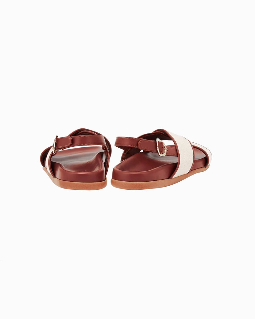 Skórzane sandały Ikesia Ancient Greek Sandals na płaskiej, profilowanej od wewnętrznej strony podeszwie z szerokimi, skrzyżowanymi paskami na górze obszytymi naturalną, płócienną tkaniną.