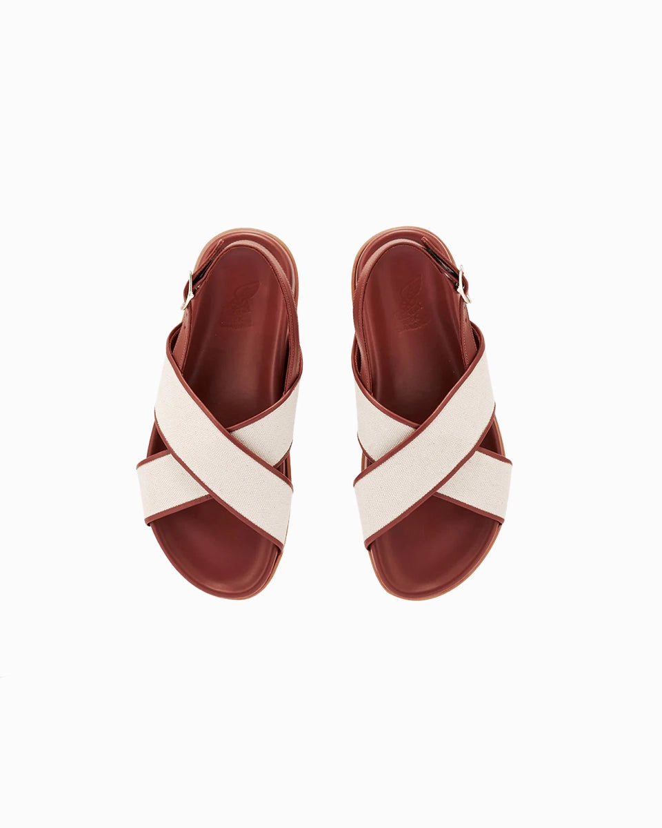 Skórzane sandały Ikesia Ancient Greek Sandals na płaskiej, profilowanej od wewnętrznej strony podeszwie z szerokimi, skrzyżowanymi paskami na górze obszytymi naturalną, płócienną tkaniną.