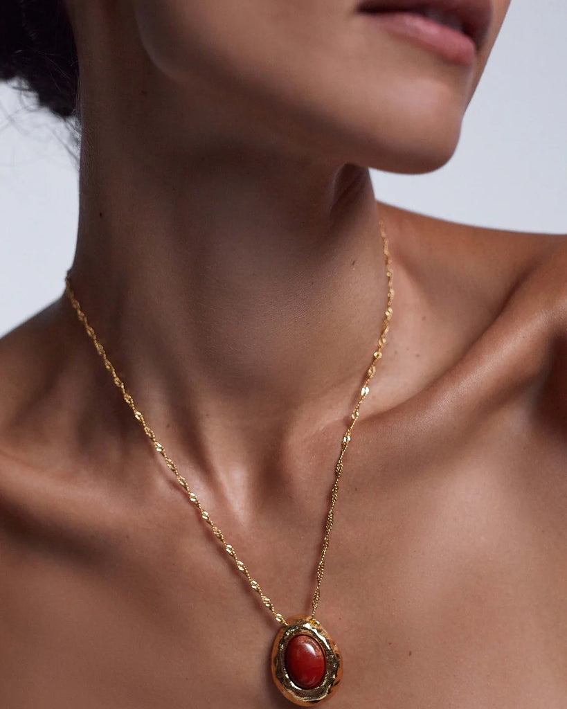 Elegancki, pozłacany naszyjnik Cherry On Top Anni Lu na długim, skręconym łańcuszku z efektowną zawieszką z dużym owalnym jaspisem. Wykończony niewielką, naturalną perłą słodkowodną.