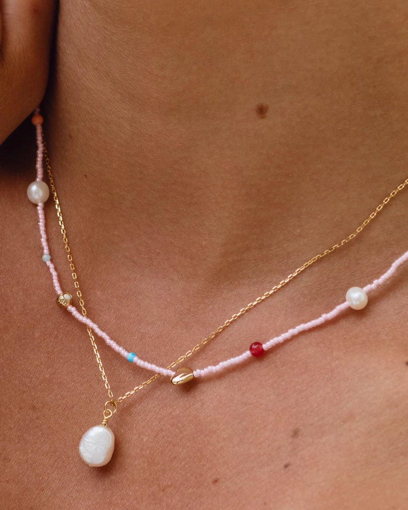 Cienki naszyjnik Oh So FIne ANNI LU z małych, różowych koralików z pozłacanym serduszkiem, naturalnymi perłami i kontrastowymi paciorkami z kamieni półszlachetnych.