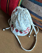 Torebka na ramię Babba Drawstring Off White marki SISSEL EDELBO z bawełny organicznej. Zmieścisz w niej niezbędne rzeczy na co dzień. Ma okrągłe dno i można ją zamknąć za pomocą sznurków. Ozdobiona jest uroczymi, niebieskimi kropkami i haftem krzyżykowym wzdłuż dolnej krawędzi, a także małym, haftowanym napisem SE.