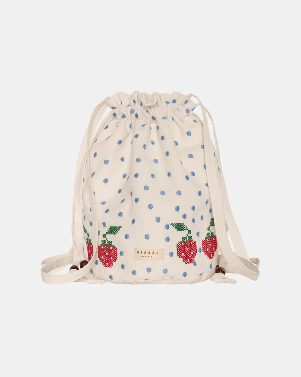 Torebka na ramię Babba Drawstring Off White marki SISSEL EDELBO z bawełny organicznej. Zmieścisz w niej niezbędne rzeczy na co dzień. Ma okrągłe dno i można ją zamknąć za pomocą sznurków. Ozdobiona jest uroczymi, niebieskimi kropkami i haftem krzyżykowym wzdłuż dolnej krawędzi, a także małym, haftowanym napisem SE.