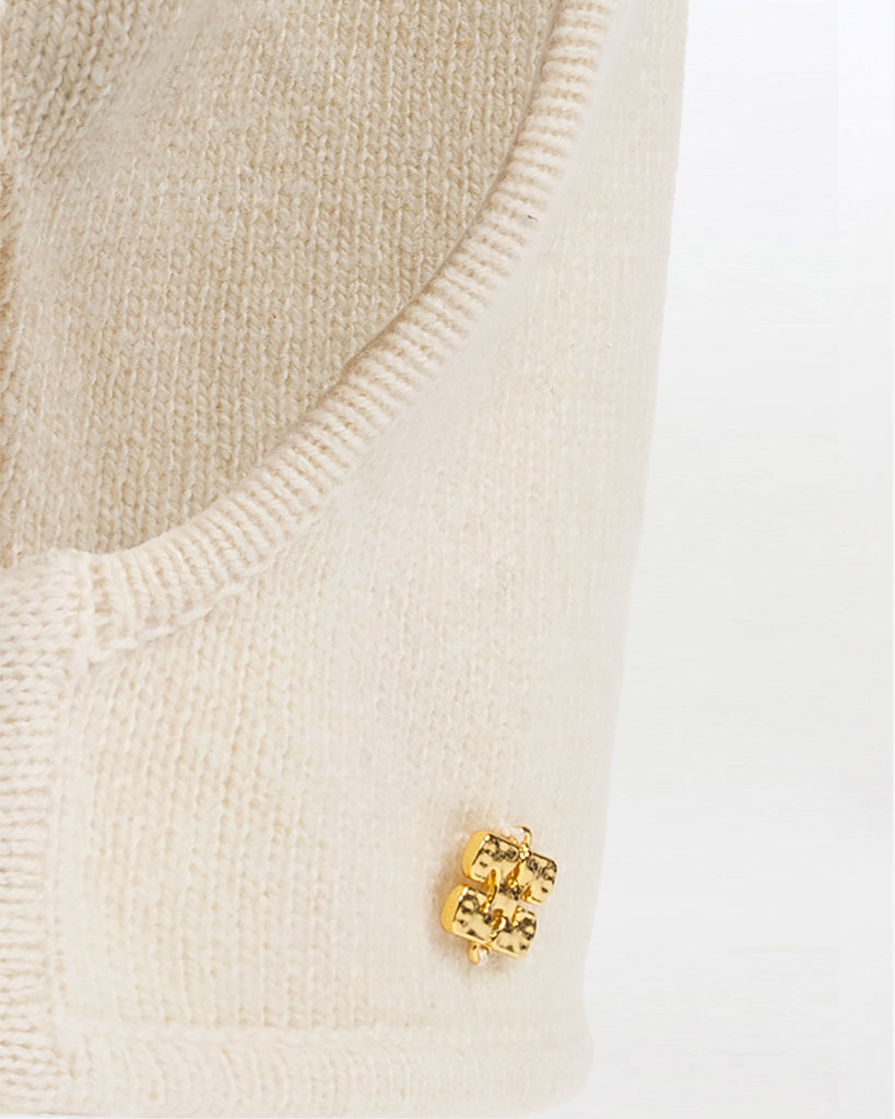 Luźna, kremowa balaclava 7205 GANNI Egret z bardzo miękkiej dzianiny z wełny. Posiada niewielką, metalową aplikację z logo marki.