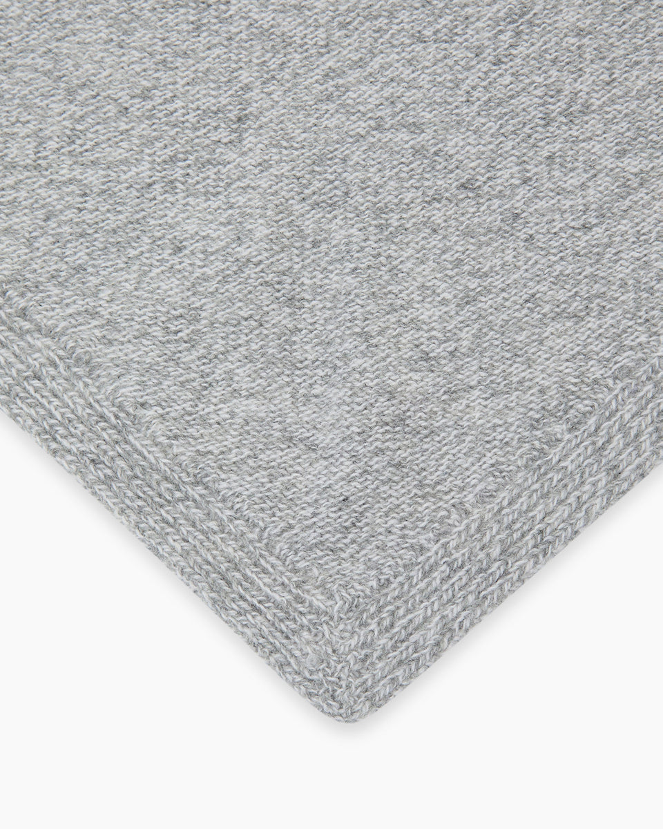 Dzianinowy, szary szalik Breeze Bandana Light Grey Melange w kształcie bandany. Składa się z trójkątnej części głównej z dłuższymi troczkami zaprojektowanymi do owinięcia pod szyją, co pozwala na naturalne i schludne układanie się materiału. Wykonany z 90% wełny merino oraz 10% kaszmiru, co zapewnia mu miękkość i ciepło.&nbsp;
