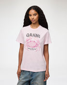 Luźny, bawełniany, różowy t-shirt BASIC COTTON JERSEY Chalk Pink GANNI z okrągłym dekoltem i krótkim, szerokim rękawem. Z przodu posiada grafikę z krabem, która wykończona jest transparentnymi koralikami oraz logo GANNI. Wykonany z miękkiej bawełny organicznej. Idealny z jeansami lub spódnicą.

-Luźny fason

-Miękka bawełna organiczna&nbsp;

-Zamów t-shirt w swoim standardowym rozmiarze. Jeśli chcesz, żeby był bardziej oversizowy - zamów go w większym rozmiarze.