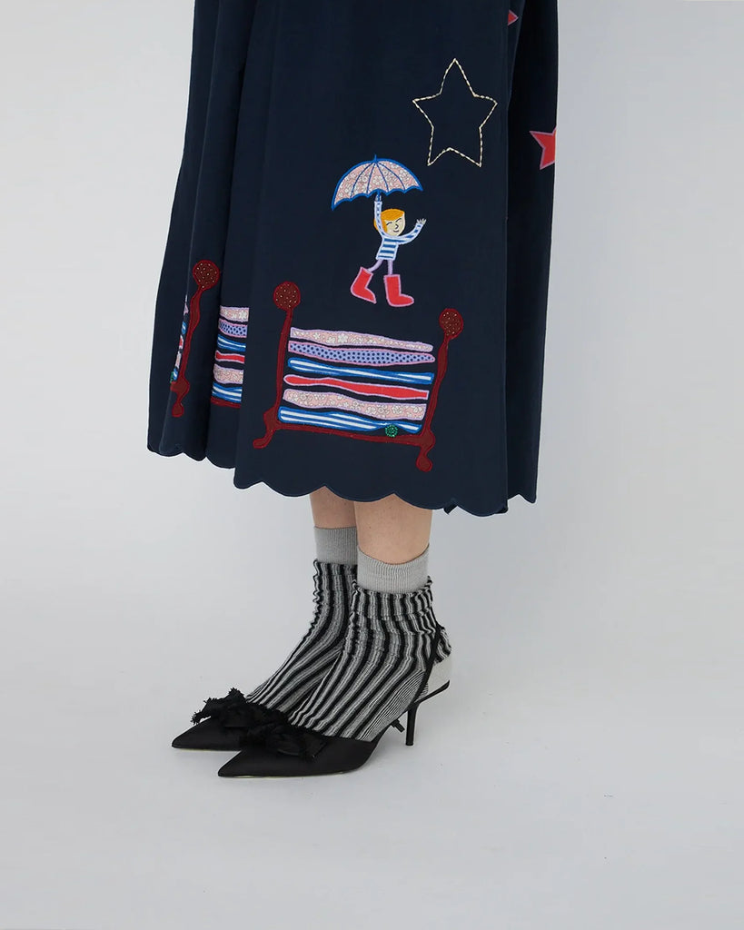 Bawełniana sukienka midi Bead Embellished Navy z uroczymi ręcznie haftowanymi motywami MIDNIGHT. Posiada dekolt w serek z zapięciem na guziki i długie, lekko bufiaste rękawy. Sukienka jest zwężana i przylegająca w talii, co pięknie podkreśla sylwetkę. Ma długość do połowy łydki. U dołu wykończona muszelkowo.&nbsp;