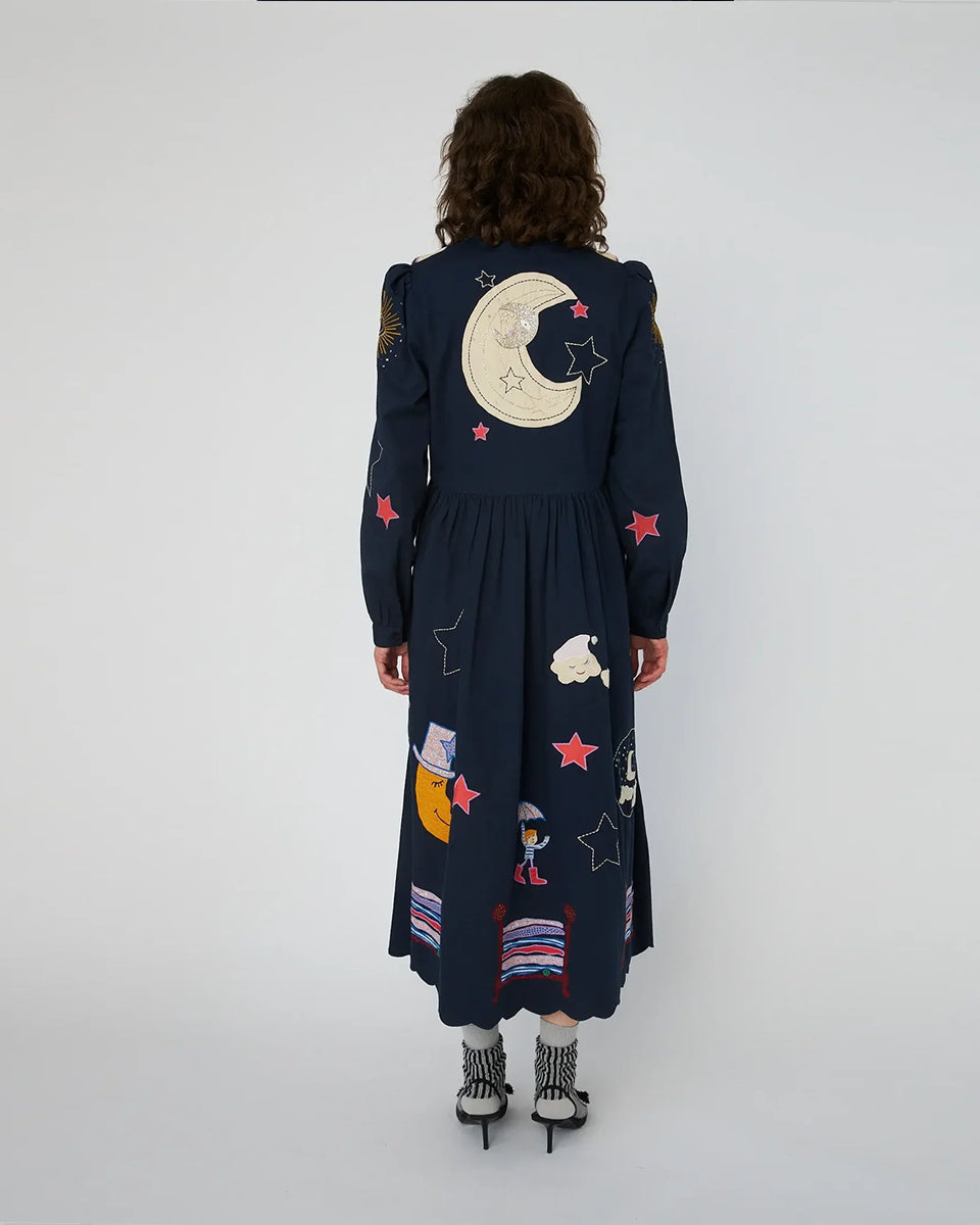 Bawełniana sukienka midi Bead Embellished Navy z uroczymi ręcznie haftowanymi motywami MIDNIGHT. Posiada dekolt w serek z zapięciem na guziki i długie, lekko bufiaste rękawy. Sukienka jest zwężana i przylegająca w talii, co pięknie podkreśla sylwetkę. Ma długość do połowy łydki. U dołu wykończona muszelkowo.&nbsp;