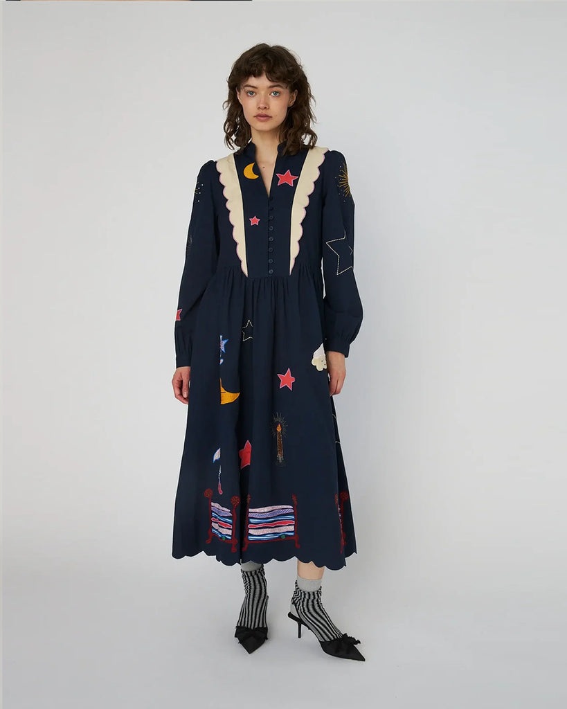 Bawełniana sukienka midi Bead Embellished Navy z uroczymi ręcznie haftowanymi motywami MIDNIGHT. Posiada dekolt w serek z zapięciem na guziki i długie, lekko bufiaste rękawy. Sukienka jest zwężana i przylegająca w talii, co pięknie podkreśla sylwetkę. Ma długość do połowy łydki. U dołu wykończona muszelkowo.&nbsp;