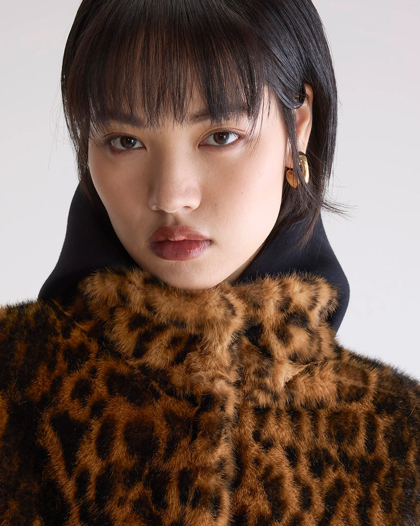 Krótka, kremowa, luźna kurtka ze sztucznego futra Enora Bellerose z wysokim, zapinanym pod szyję kołnierzem i luźnymi, reglanowymi rękawami zakończonymi elastycznymi ściągaczami.