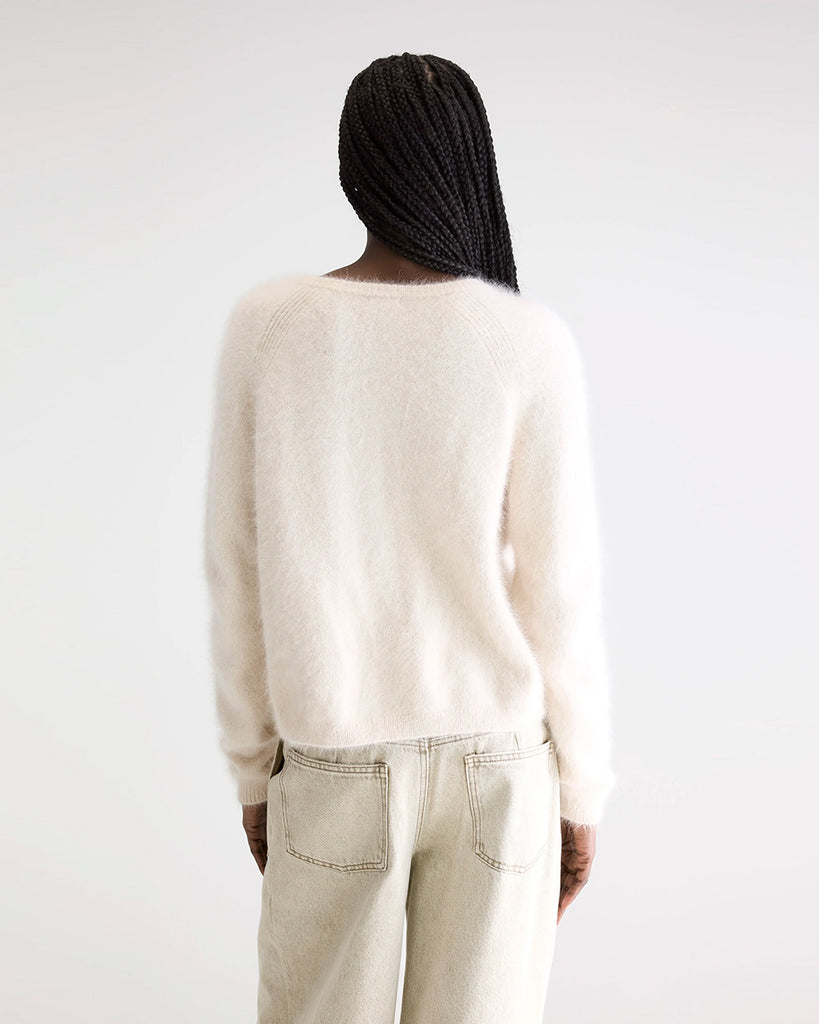 Prosty, krótki, kremowy kardigan Datair Bellerose z okrągłym dekoltem. Wykończony ściągaczami. Zapinany na guziki. Sweter ma prosty krój i wykonany jest z bardzo miękkiej i puchatej dzianiny z angorą