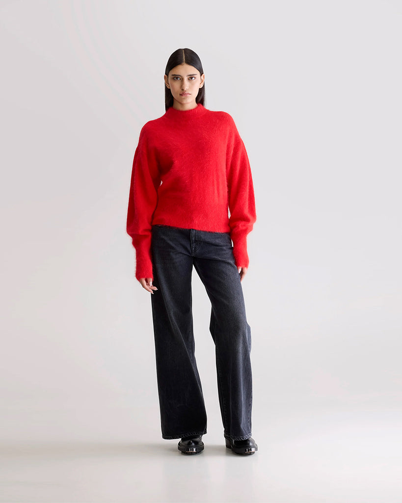 Prosty, krótki, czerwony sweter Dateka Bellerose z okrągłym dekoltem, opadającymi ramionami i szerokimi rękawami zakończonymi długimi, wąskimi ściągaczami. Sweter ma prosty krój i wykonany jest z bardzo miękkiej i puchatej dzianiny z angorą.