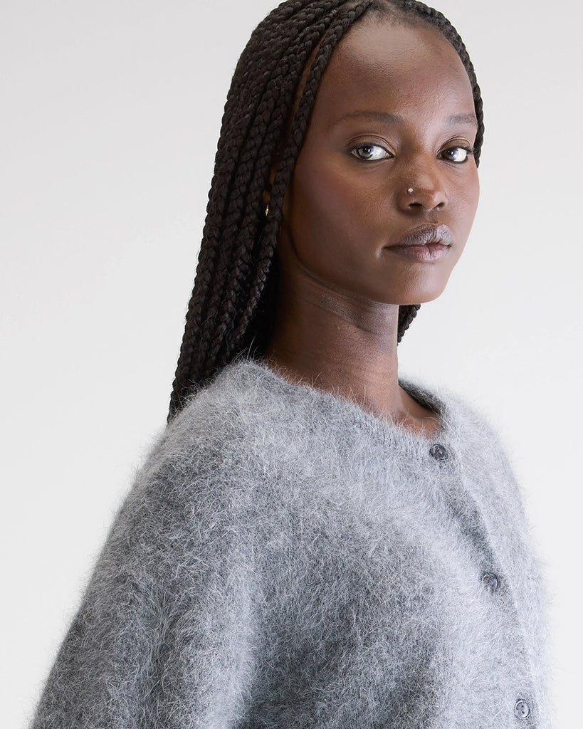 Prosty, szary kardigan Dathan Bellerose z okrągłym dekoltem i opadającymi ramionami. Wykończony ściągaczami. Zapinany na czarne guziki. Sweter ma prosty krój i wykonany jest z bardzo miękkiej i puchatej dzianiny z angorą