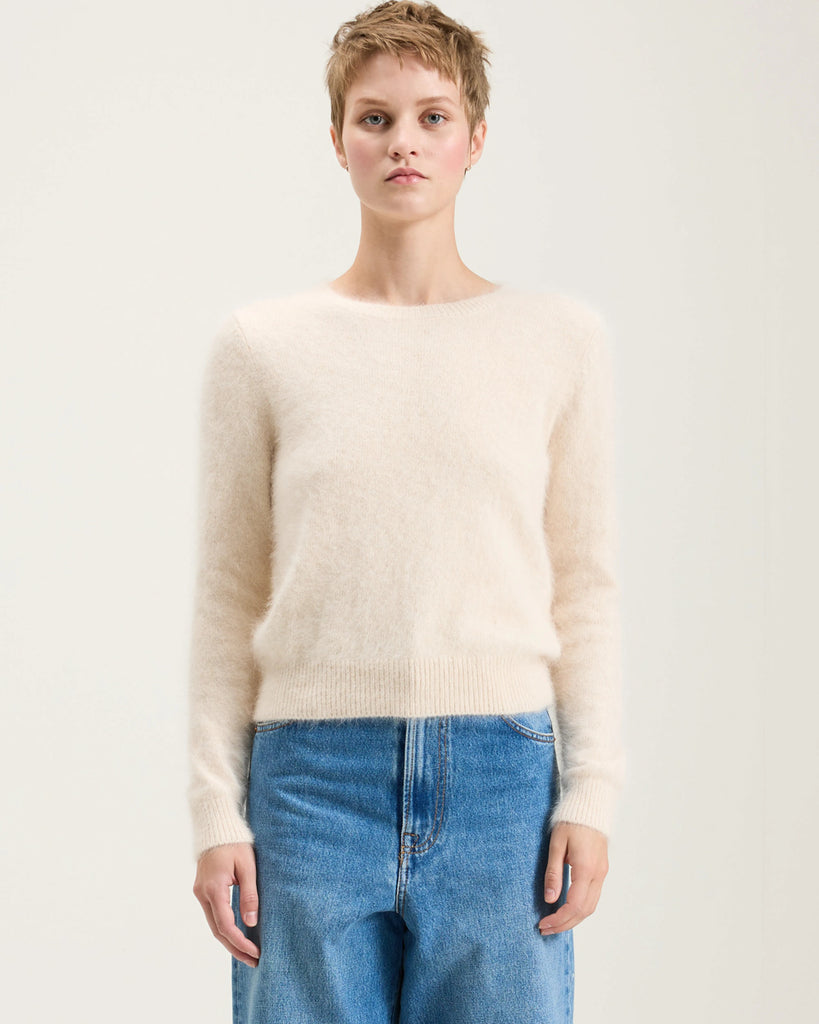 Prosty, krótki, fioletowy sweter Datti Bellerose z okrągłym dekoltem. Wykończony ściągaczami. Sweter wykonany jest z bardzo miękkiej i puchatej dzianiny z angorą.