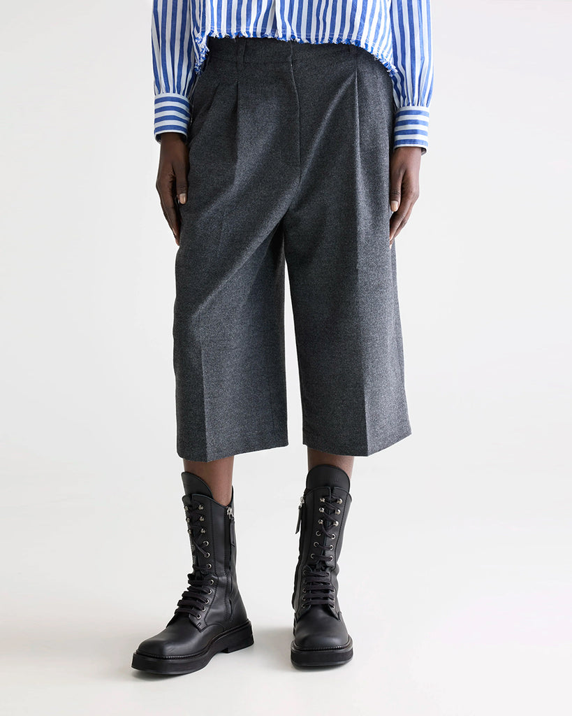 Garniturowe bermudy Dom Bellerose z wysokim stanem i zakładkami. Szorty mają szeroką, prostą nogawkę, dwie boczne i dwie tylne kieszenie. Spodnie mają długość za kolana. 