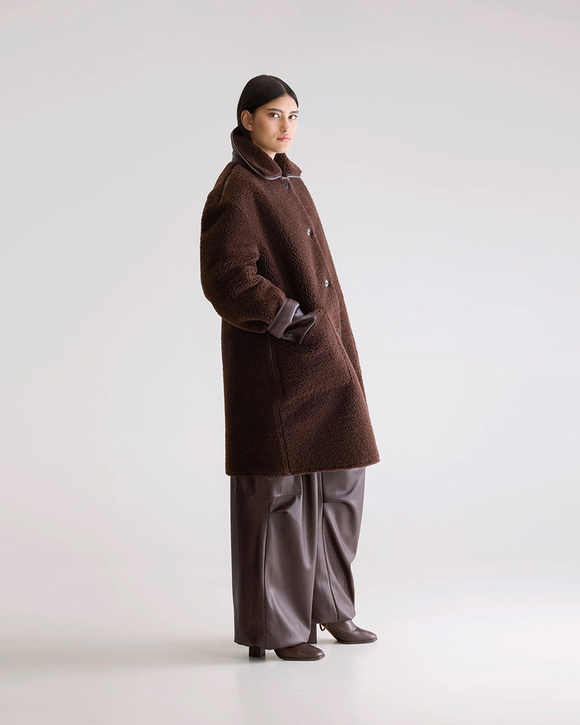 Długi, dwustronny ekologiczny kożuch Easton Bellerose z kołnierzem, opadającymi ramionami i wywijanymi rękawami. Z przodu posiada dwie, duże kieszenie. Zapinany na guziki. Z jednej strony wykonany z gładkiej imitacji skóry, z drugiej ze sztucznego, miłego w dotyku "misia".