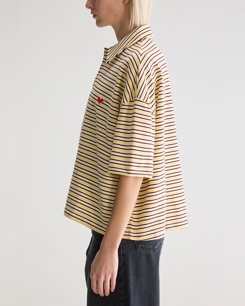 Luźna, pudełkowa koszulka polo Foolo Bellerose w paski. Posiada kołnierzyk, opadające ramiona i krótki, szeroki rękaw o długości do łokci. Pod szyją zapinana na guziki.